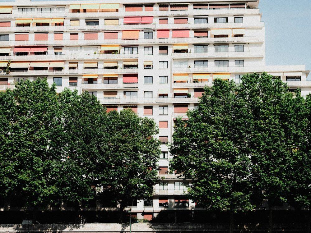 Façade d’une grande copropriété résidentielle bordée d’arbres